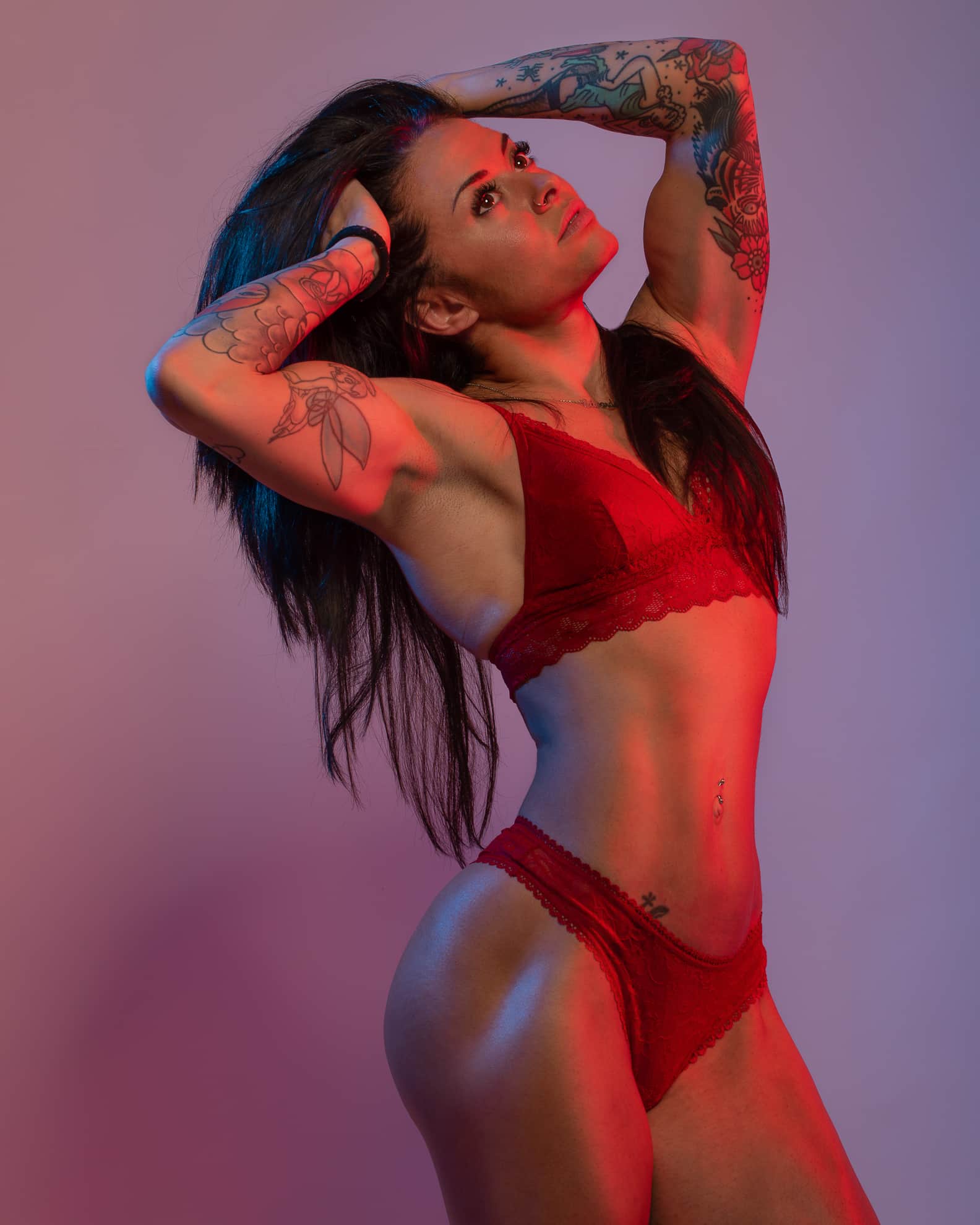 ragazza muscolosa tatuata indossa intimo rosso in studio fotografico