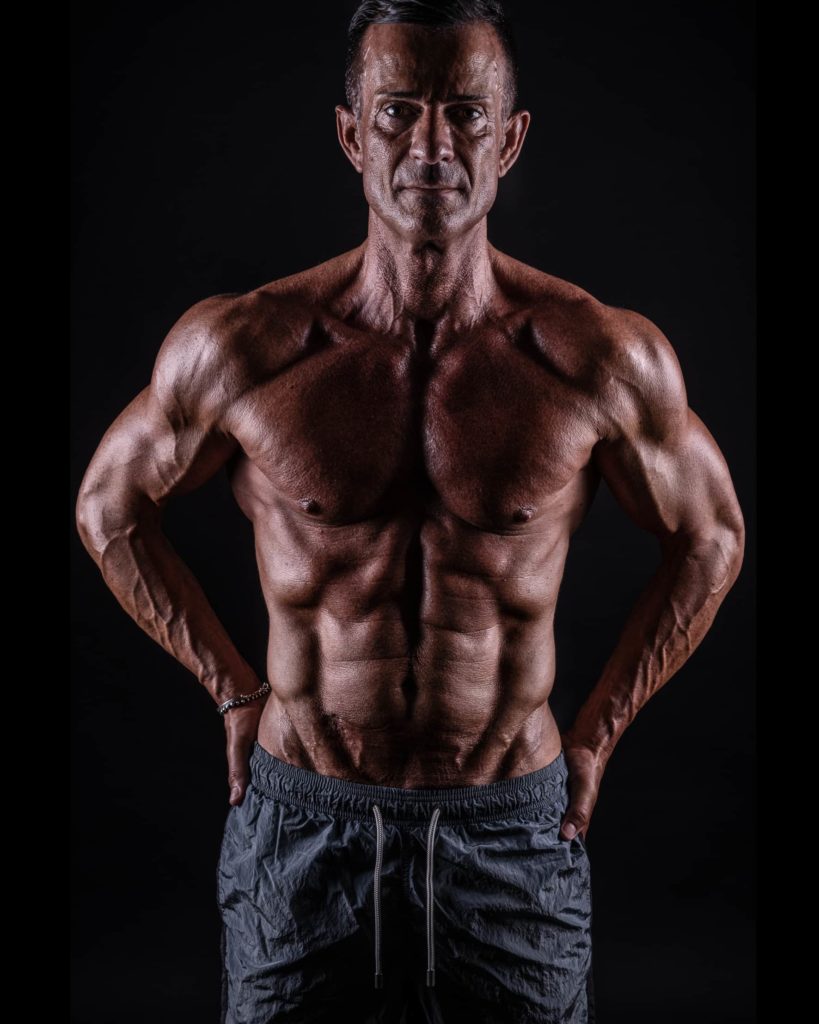 fotografofitness studio fotografico ragazzo con busto muscoloso e pantaloncini su sfondo nero