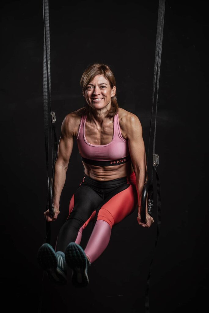 ragazza muscolosa mentre fa gli anelli in palestra sorridendo