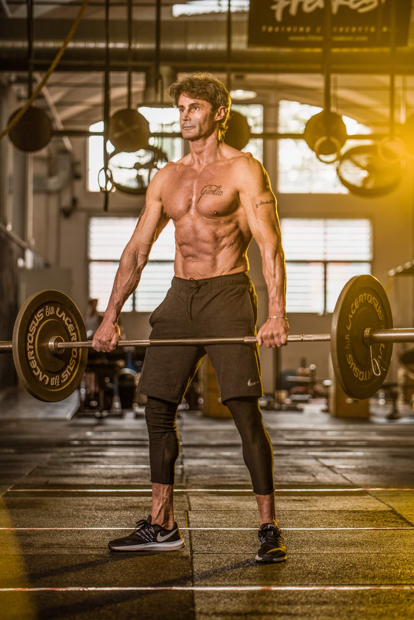 portfolio fotografo fitness uomo muscolo esegue esercizio in palestra luce gialla gel colorata
