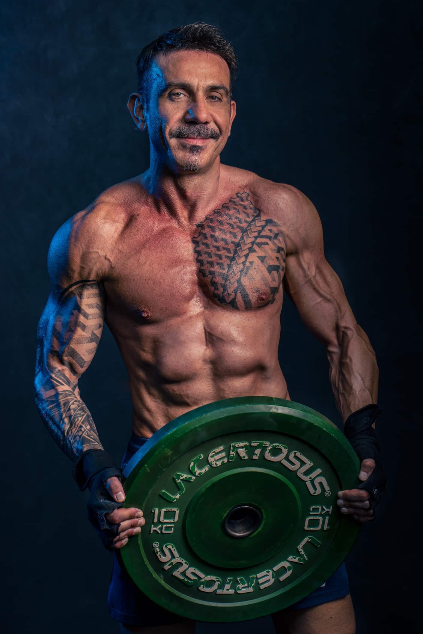 uomo muscoloso tiene in mano disco bilanciere fotografo fitness